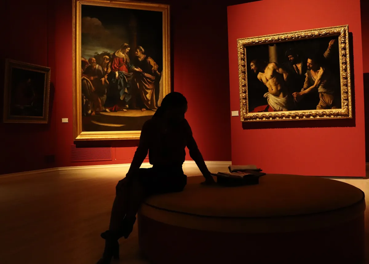 Visiteuse devant des tableaux de maîtres dans un musée