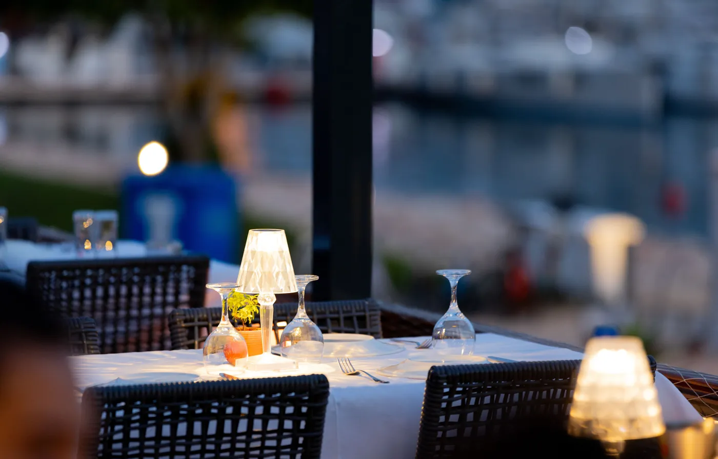 Table dressée sur une terrasse au bord d'une marina, au crépuscule