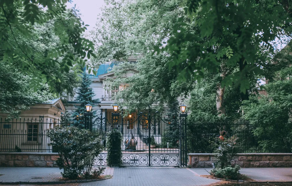 Portail en fer forgé d'une demeure privée, entre les arbres