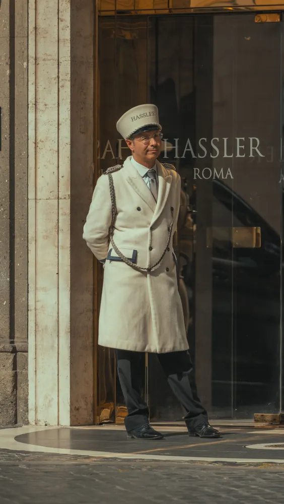 Portier en uniforme devant l'entrée d'un grand hôtel à Rome